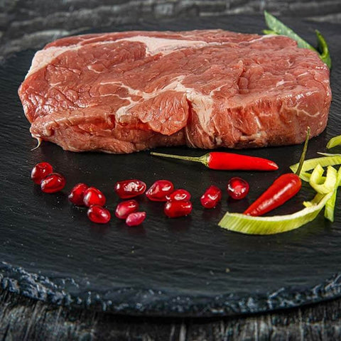 Rohes Entrecôte-Steak auf schwarzer Schieferplatte mit Chili und Lauchstreifen