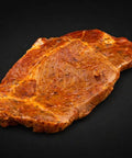 Mariniertes Schweinehalssteak mit Gewürzen auf dunklem Hintergrund